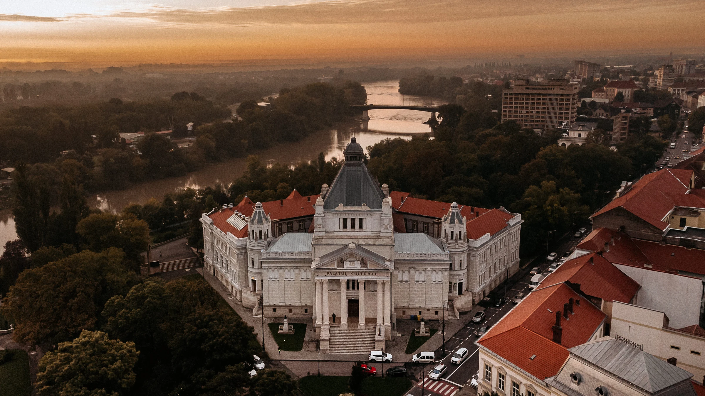 Vedere aeriană a Palatului Cultural Arad, cu fațada principală și Mureșul în fundal, în lumină caldă